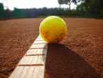 A picture of a tennis ball laying on the court